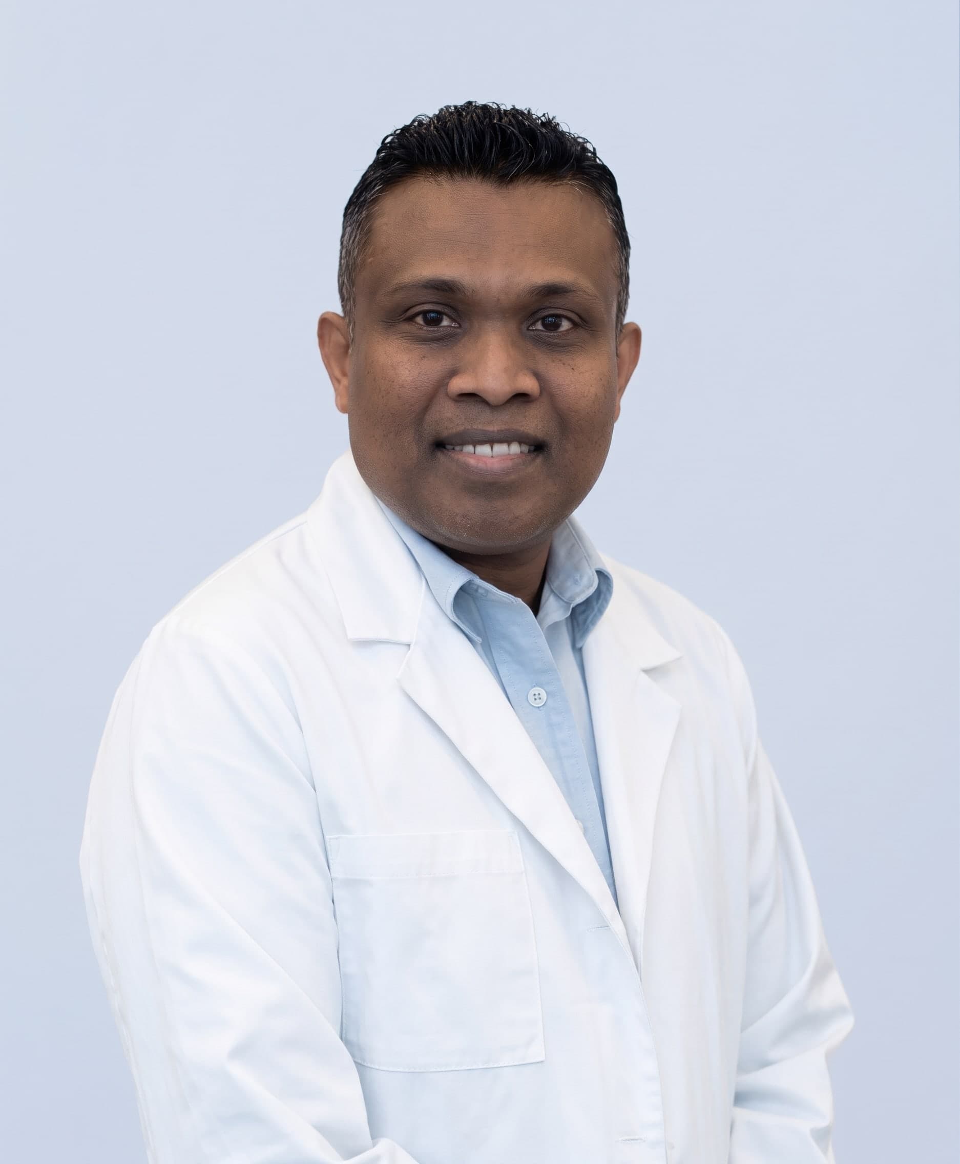 Dr. Savinda Morais, ND, in a white lab coat at his Hamilton clinic